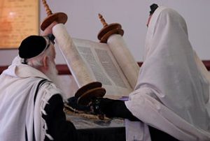 Two Jewish men holding an open Torah scroll